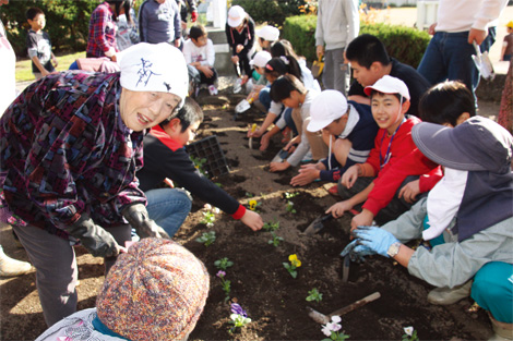 原発事故による避難生活を続ける子どもたちと、会津若松市河東地区のボランティア「河東大熊フレンズ」の皆さんとの花の苗の植え付け作業の様子